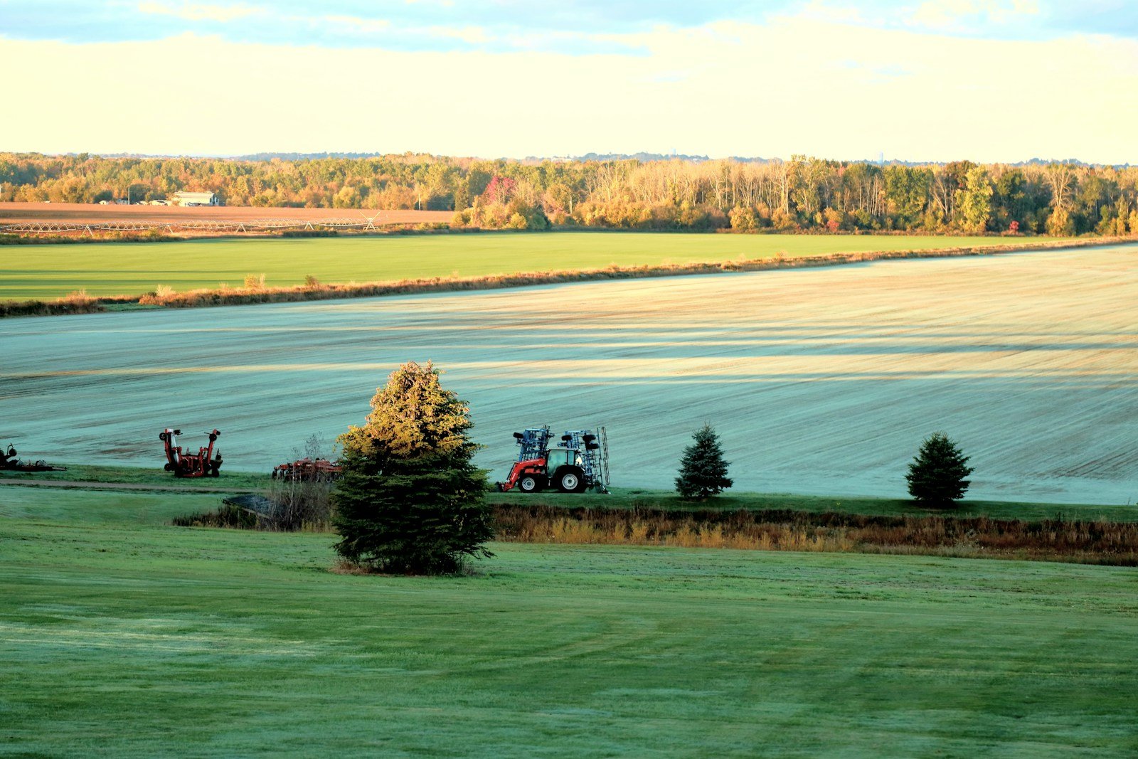 Tractor working in a paddock with trees in the background